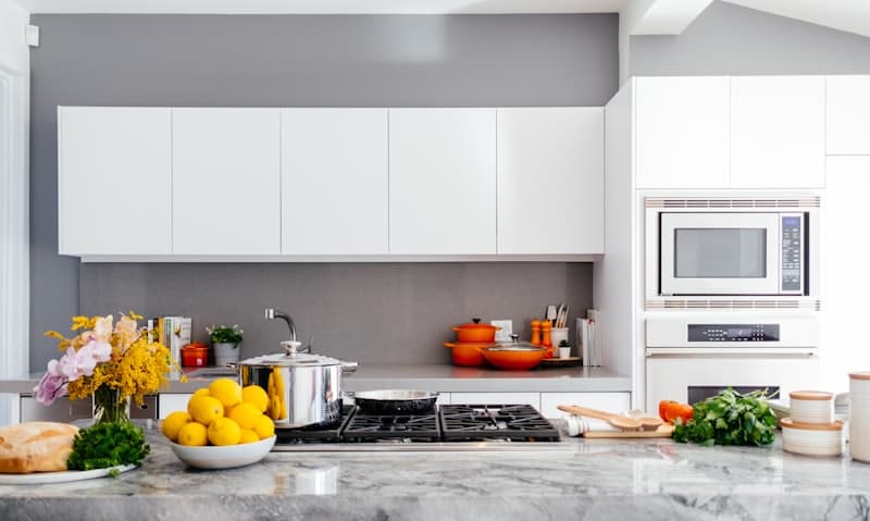 Spotless white kitchen with fresh lemons and flowers on the counter